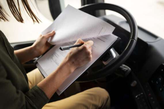 Female truck driver sitting in the vehicle cab with transport documents